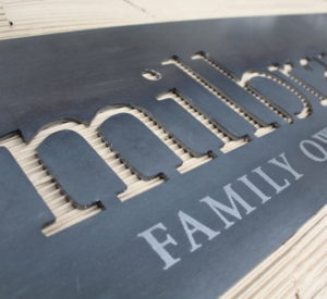 Milbrandt Family - raw steel with rubbed oil, "FAMILY" is etched glass vinyl, backed with corrugated cardboard for visual interest