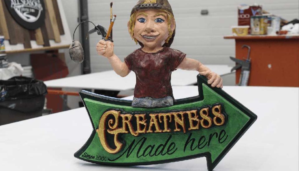 3D sign saying Greatness Made Here with sculpted woman holding a paint brush and pencil.