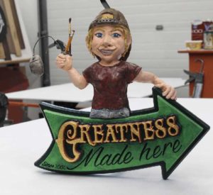 3D sign saying Greatness Made Here with sculpted woman holding a paint brush and pencil.