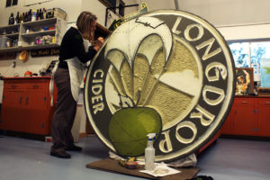 woman painting large round sign