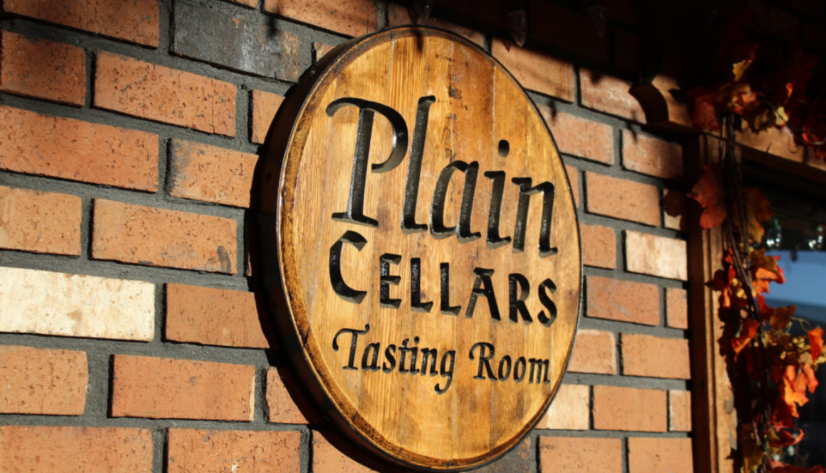 Round wood sign with black carved letters on a brick wall.